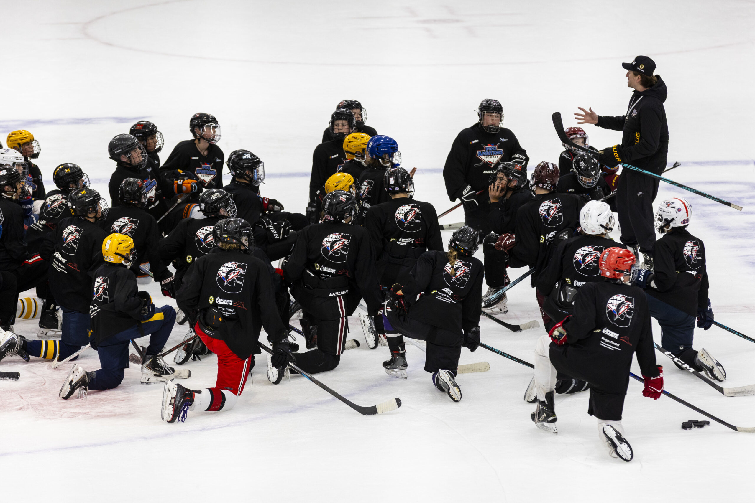 Pro Ambitions team huddle on ice at Norwich University
